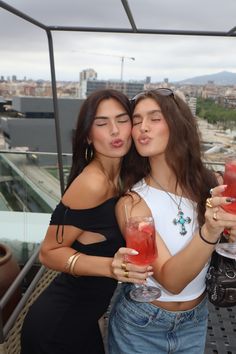 two women standing next to each other holding drinks