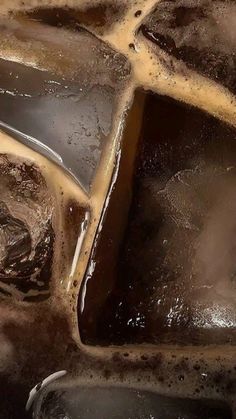 some brown and black ice cubes on top of each other with water running down them