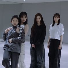 four young women standing in front of a mirror with their arms around each other's shoulders