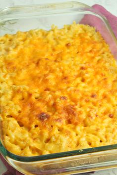 a casserole dish with cheese in it on a pink napkin next to a fork