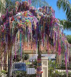 a tree covered in colorful streamers next to a fence