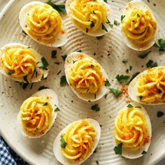 several deviled eggs on a white plate with parsley