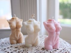 three small candles sitting on top of a doily next to a window sill