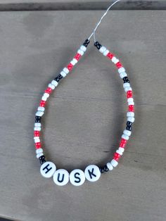 a red, white and black beaded necklace with the word husk on it