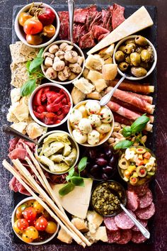 a platter filled with meats, olives, tomatoes and other food items