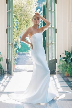 a woman in a white wedding dress posing for a photo with her hand on her head