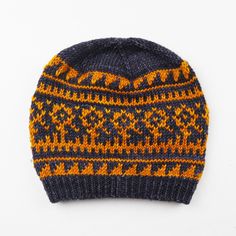 a knitted hat with an orange and blue pattern on the front, against a white background