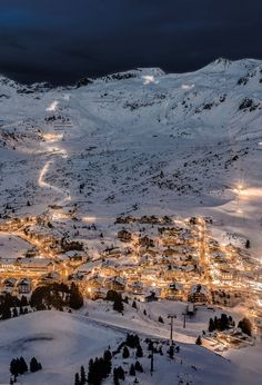 an aerial view of a ski resort at night with lights on the snow covered slopes