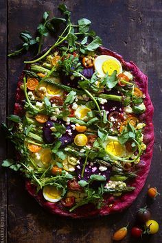 a pizza topped with lots of veggies on top of a wooden table