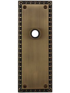 an antique brass door handle with black circles on the front and center, against a white background