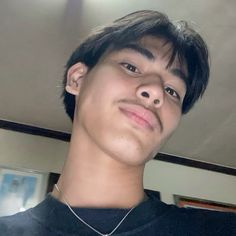 a young man is wearing a black shirt and has a silver necklace on his neck