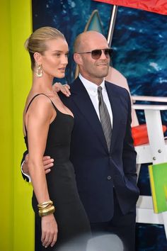 a man and woman standing next to each other in front of a green wall at an event