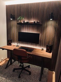 a desk with a monitor and speakers on it in front of a wooden paneled wall