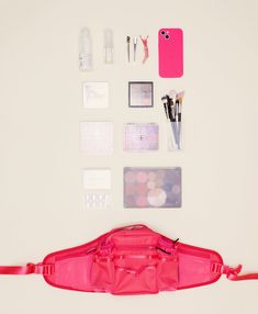 the contents of a pink purse laid out on a white surface