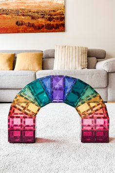 a rainbow colored glass arch sitting on top of a white rug in front of a couch