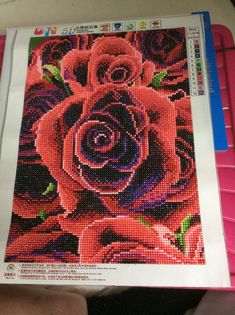 there is a cross stitch picture of a pink rose on the front of a magazine