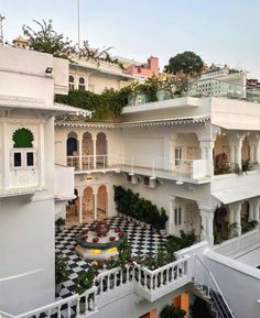 an outdoor courtyard with several balconies and plants on the top floor, surrounded by white buildings