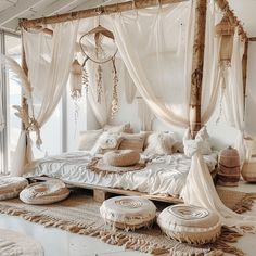 a canopy bed with white sheets and pillows