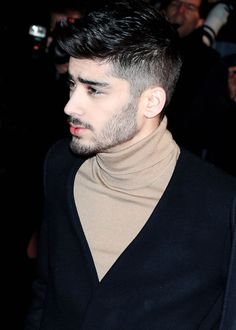 a close up of a person wearing a turtle neck sweater and looking off to the side