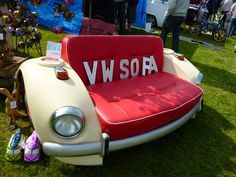 an old vw bug is parked in the grass with people looking at cars and other items