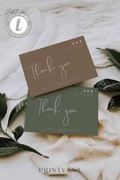 two thank cards sitting on top of each other next to some green leafy leaves