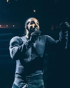 a man standing in front of a microphone holding his hand up to the side while singing