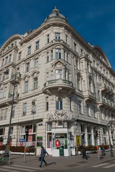 a tall building with lots of windows on top of it's sides and people walking around