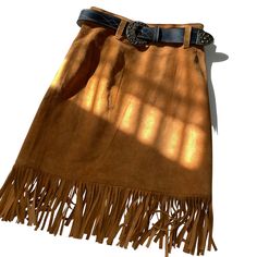 This 80s Cedars leather skirt features a western style with fringes and a belt. The soft leather material makes it comfortable to wear and the brown color gives it a classic look. The skirt is in great shape and has been well-maintained over the years. The skirt is a size 6 and fits true to size. The Cedars brand is known for their quality leather products and this skirt is no exception. Perfect for a vintage or western-inspired look, this skirt is a must-have for any fashion-forward individual. Leather Skirt With Belt Loops For Fall, Fall Brown Belted Skirt, Western Style Brown Bottoms For Fall, Brown Fringe Mini Skirt, Leather Products, Winter Sale, Western Style, Belt Size, Leather Material