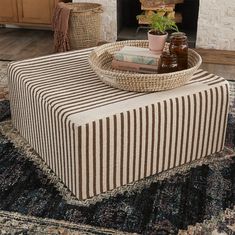 a striped ottoman sits in front of a fire place with bottles on it and a potted plant