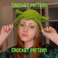 a woman with red hair wearing a knitted yoda hat and green eyeshade