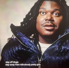 a man with dreadlocks is looking at the camera while wearing a blue jacket