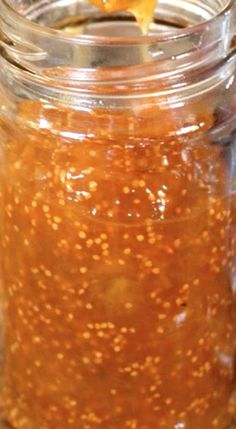 a spoon with some food in it on top of a glass jar filled with liquid