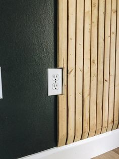 an electrical outlet on the wall next to a wooden slatted paneling door