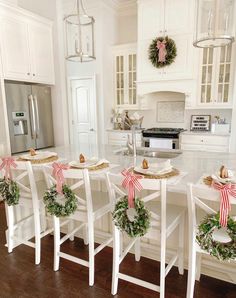 the kitchen is decorated for christmas with wreaths on the island and garland around the chairs