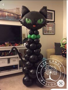 a black cat balloon sitting on top of a pile of black balloons in front of a tv