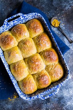 a blue and white baking dish filled with bread rolls next to a bowl of mustard