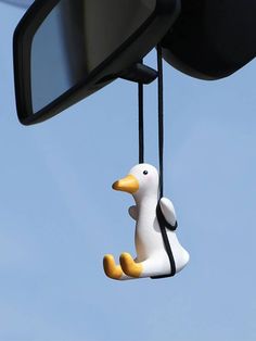 a duck hanging from the side mirror of a car in front of a blue sky