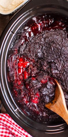 cranberry sauce in a slow cooker with a wooden spoon next to it