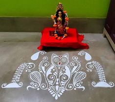 a small statue sitting on top of a red table next to a white painted floor