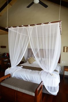 a bed with white drapes hanging from the ceiling