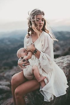 a woman holding a baby on top of a mountain