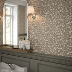 a bathroom sink sitting under a mirror next to a wall mounted faucet with soap dispensers on it