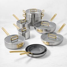 an assortment of pots and pans with gold handles