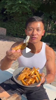 a man is eating french fries on a plate and holding a piece of bread in his hand