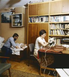 two people sitting at a desk in front of bookshelves and a book shelf