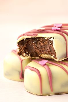 three pieces of chocolate cake with white frosting and pink sprinkles on top