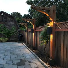 a wooden fence with lights on it and some plants growing out of the top posts