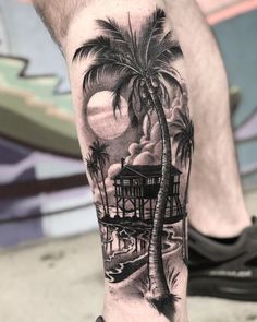 a man's leg with a palm tree and house tattoo on the side of his arm