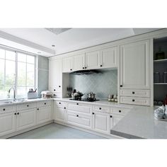 a kitchen with white cabinets and marble counter tops