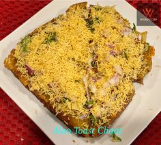 a square white plate topped with food on top of a red table